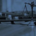 Blue tinted scales of justice on a table in a blurry courtroom