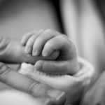 Infant holding an adult finger