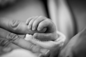 Infant holding an adult finger